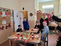 4. Dzieci siedzą przy stole opiekunka otwiera szampana 