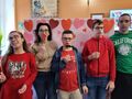 2. Uczniowie z wychowawcą pozują do zdjęcia na tle walentynkowej ścianki 