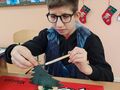 2. Chłopiec maluje drewniane choinkę 