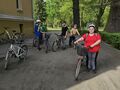 wychowankowie stoją przed szkołą na zewnątrz przy swoich rowerach mają kaski na głowach
