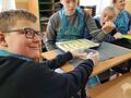 5. Chłopiec smaruje jajkiem paluchy czosnkowo serowe koledzy się przyglądają. kopia