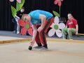 chłopiec toczy kulę do bocce na łace siedzi dziewczynka