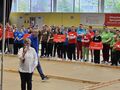 rozpoczecie zawodów do mikrofonu przemawia pani w tle zawodnicy z różnych klubów