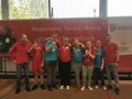 uczniowie i dwóch nauczycieli pozują do zdjęcia stoją na tle baneru Regionalny Turniej Bocce Olimpiad Specjlanych