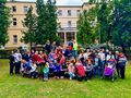 zdjęcie grupowe uczniowie oraz nauczyciele stoją w parku w tle budynek szkoły
