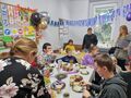 Uczniiowie świętują urodziny kolegi spożywając tort i smakołyki