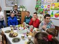 Uczniowie siedzą przy stole urodzinowym z tortem