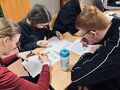 3. Dwie uczennice i trzech uczniów. Siedzą przy stoliku i rowziązują wykreślankę 