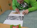 uczeń maluje kartkę klejem