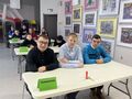 1. Uczniowie siedzą przy stolikach uśmiechają się 