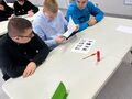 3. Trzej chłopcy siedzą przy stoliku jeden z nich wycina nożyczkami 