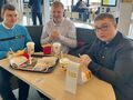 7. Trzech uczniów siedzi w restauracji przy stoliku na stole jedzenie 