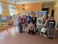 uczestnicy konkursu razem z dyrekcją i nauczycielami pozują do zdjęcia w holu w tle wystawa prac konkursowych