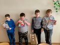Na zdjęciu widocznych jest 4 chłopców którzy trzymaja w rękach dyplomy oraz nagrody. Dzieci uczestniczyły w konkursie pt. Najciekawsza zakład