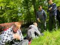 uczniowie siedza na trawie w lesie z tyłu mostek