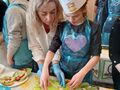 Nauczycielka pomaga uczestniczce konkursu Master Chef przygotować pyszną sałatkę. 