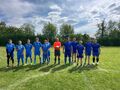 grupa zawodników i sędzia stoją w szeregu na boisku