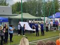 zawodnicy z zsskrotoszyn wciągają flagę olimpiad specjalnych zawodnicy oraz zaproszeni goscie obserwują to wydarzenie