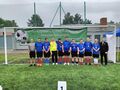 zdjęcie grupowe zawodnicy i trenerzy sosw konarzew na tle napisu XXII regionalny turniej piłki nożnej olimpiad specjalnych