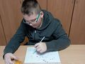 uczeń siedzi przy ławce w klasie i maluje barwnikami