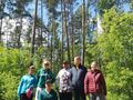 uczniowie stoją przy drzewach w lesie 