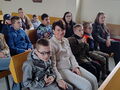 uczniowie i nauczyciele siedzą w ławkach w kościele