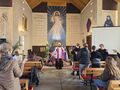 uczniowie razem z o. Walentym na rekolekcjach w kościelestoją i ilustrują gestami piosenkę rekolekcyjną w tle duży obraz Jezusa Miłosiernego