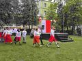 uczniowie wraz z nauczycielami tańczą Poloneza na boisku szkolnym