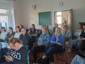 rodzice siedzą przy ławkach w klasie i słuchają wykładu