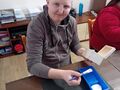 uczeń siedzi przy stole w pracowni i maluje skrzynkę