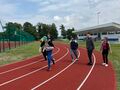 uczniowie biegną po bieżni stadionu