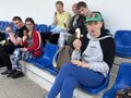 uczniowie siedza na trybunach stadionu i jedzą lody