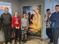 1. Pięcioro uczniów pozuje w kinie przy plakacie filmu Królewny Śnieżki