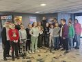 2. Uczniowie z nauczycielami pozują w kinie przy plakacie filmu Królewny Śnieżki 