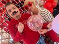 8. Uczeń z nauczycielka pozują na tle fotościanki walentynkowej 