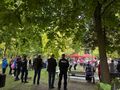 zaproszeni goście oraz harcerze wspólnie śpiewają i wykonują pląsy stoją w kole wokół ogniska w parku