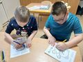 Chłopcy kolorują kredkami misia
