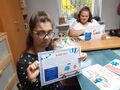 Uczennice siedzą prxy stole pokazuj zdjęcia 