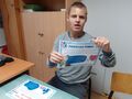 Uczeń siedzi przy stole pokazuje zdjęcie 