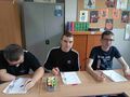 uczniowie siedzą przy ławce w klasie i wykonują ćwiczenie