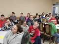 6 uczniowie rodzice i nauczyciele siedzą na krzesłach przy stołach na sali wiejskiej