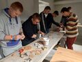 uczniowie stoja przy stole i dekorują ozdoby