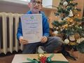 chłopiec trzyma dyplom a przed nim leży zamknięta paczka z nagrodami