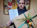 chłopiec stoi przy ścianie i trzyma w ręku dyplom i paczkę