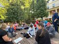 Uczniowie siedzą na scenie i robią zadania