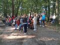 3. niektórzy uczniowie stoją inni siedzą na ławkach w parku przy figurze Matki Bożej