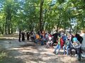 7. niektórzy uczniowie stoją inni siedzą na ławkach w parku przy figurze Matki Bożej