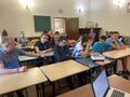 Uczniowie siedzą przy ławkach w klasie i biorą udział w pogadance na temat wykorzystywania seksualnego