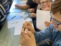 Uczniowie siedzą przy ławkach w klasie i biorą udział w ćwiczeniu aktywizującym