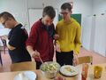 dwóch uczniów nakłada w naleśnik sałatkę